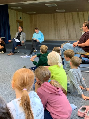Die Gemeindedetektive der Wilhelm-Schussen-Grundschule hören Bürgermeister Schellinger in einem Sitzkreis zu