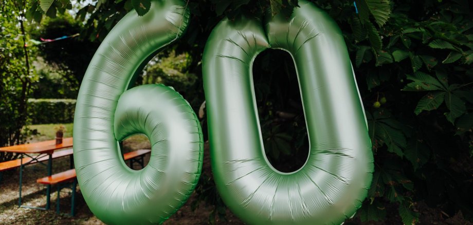 Grüne Luftballons in Form einer sechzig hängen an der Hecke des Kindergartens Brochenzells