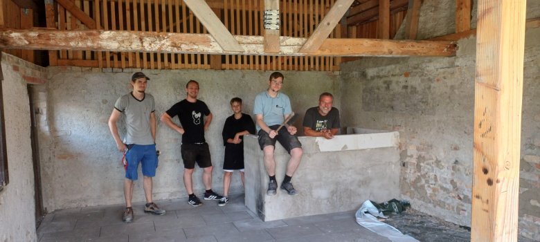 Vertreter des Jugendrates, Nils Kaeding und ein Mann einer Maurerfirma lächeln in dem Fertig renovierten Jugendhaus in Kehlen in die Kamera