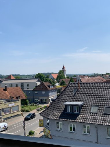 Adlerkreuzung in Meckenbeuren Autos fahren über die nicht sehr belebte Straße, vom Dach fotografiert. Man sieht den Kirchturm St. Maria. 