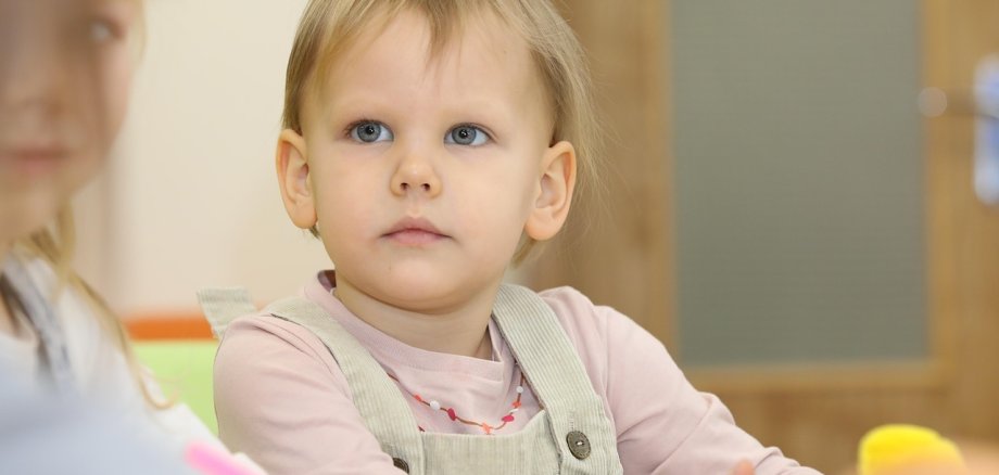 Ein kleines Kindergartenkind schaut zur Erzieherin