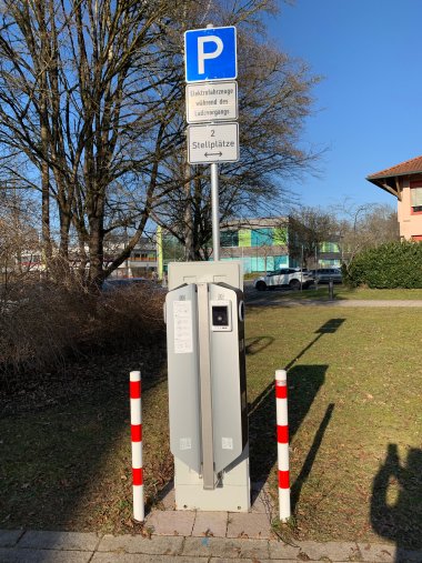 Ladesäule Wirelane Am Rathaus Meckenbeuren steht eine E-Ladesäule mit zwei Ladeplätzen bereit. Im Hintergrund das Bildungszentrum Meckenbeuren
