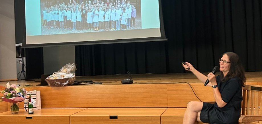 Frau Wiedmann zeigt im sitzen, eine Diashow wie das BZM entstanden ist