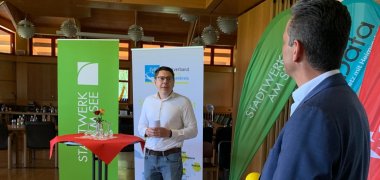 Teilnehmer des symbolischen Startschusses weiße Flecken im Trauzimmer der Gemeinde Meckenbeuren vor Stehtischen und Holzwand