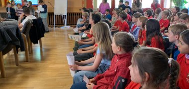 Grundschüler zum Teil in roten T Shirts im Großen Sitzungssaal der Gemeinde tragen etwas vor