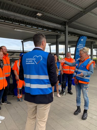 GRuppenbild auf dem Bahnhofsvorplatz Meckenbeuren mit Blumen und Menschen, die saubermachen
