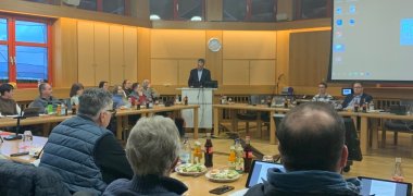 Großer Sitzungssaal des Rathauses holzvertäfelt mit Menschen 