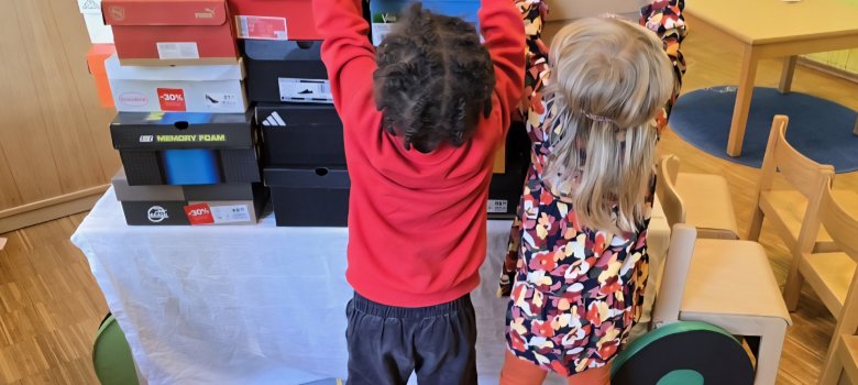 Kinder in bunten T-Shirts spielen Umzug mit Kisten