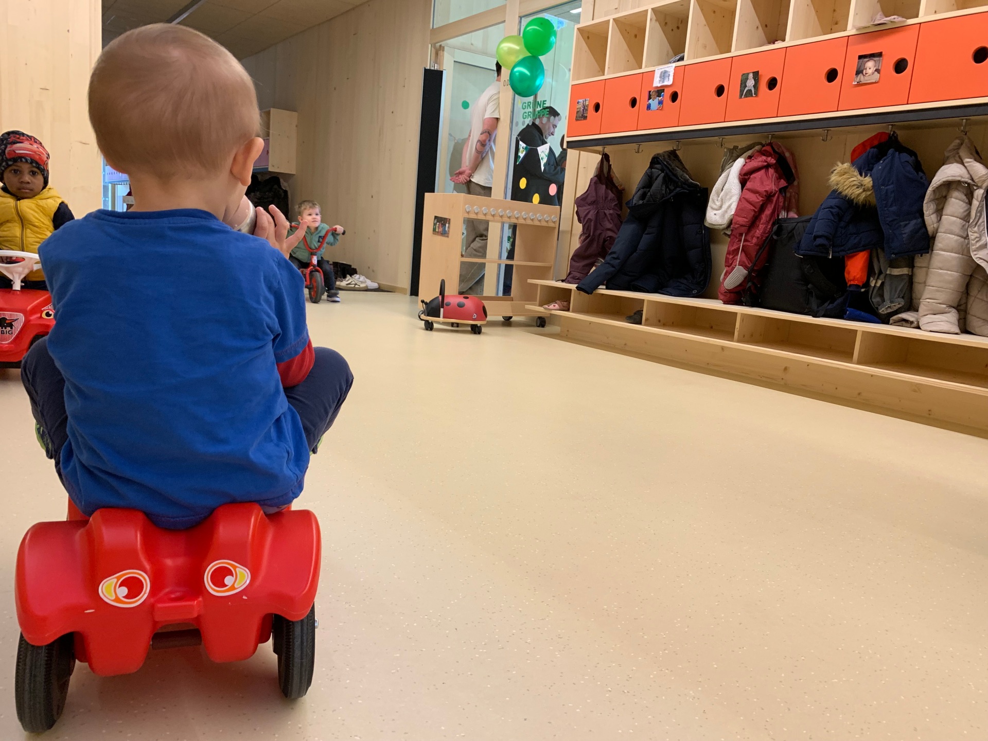 Weißtanneholzwände in der Kita mit Kind auf rotem Bobbycar