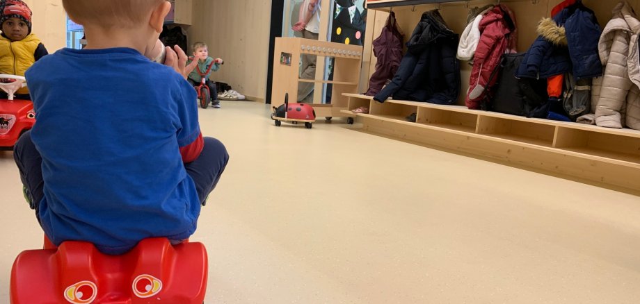 Weißtanneholzwände in der Kita mit Kind auf rotem Bobbycar
