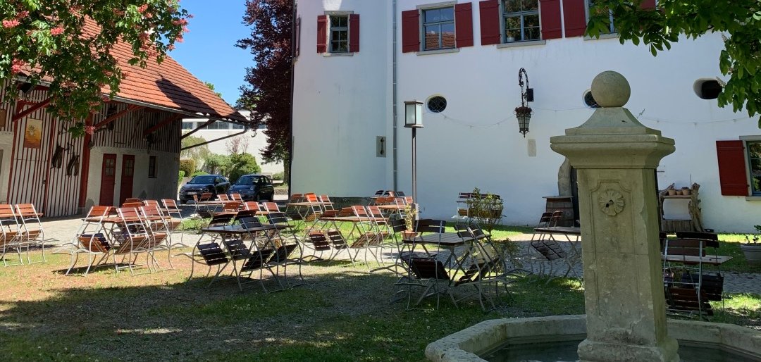 weiße Außenfassade des etwa 500 Jahre alten Schloss Brochezell mit Türmen und Brunnen davor