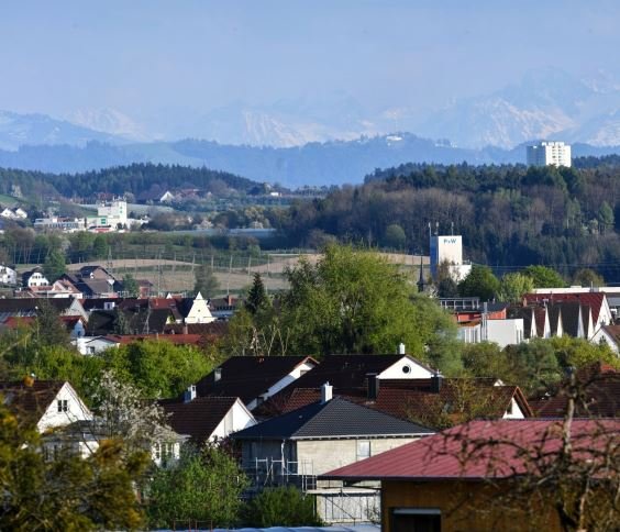 Luftaufnahme vom Ort mit Bergen und Kirche im Hintergrund